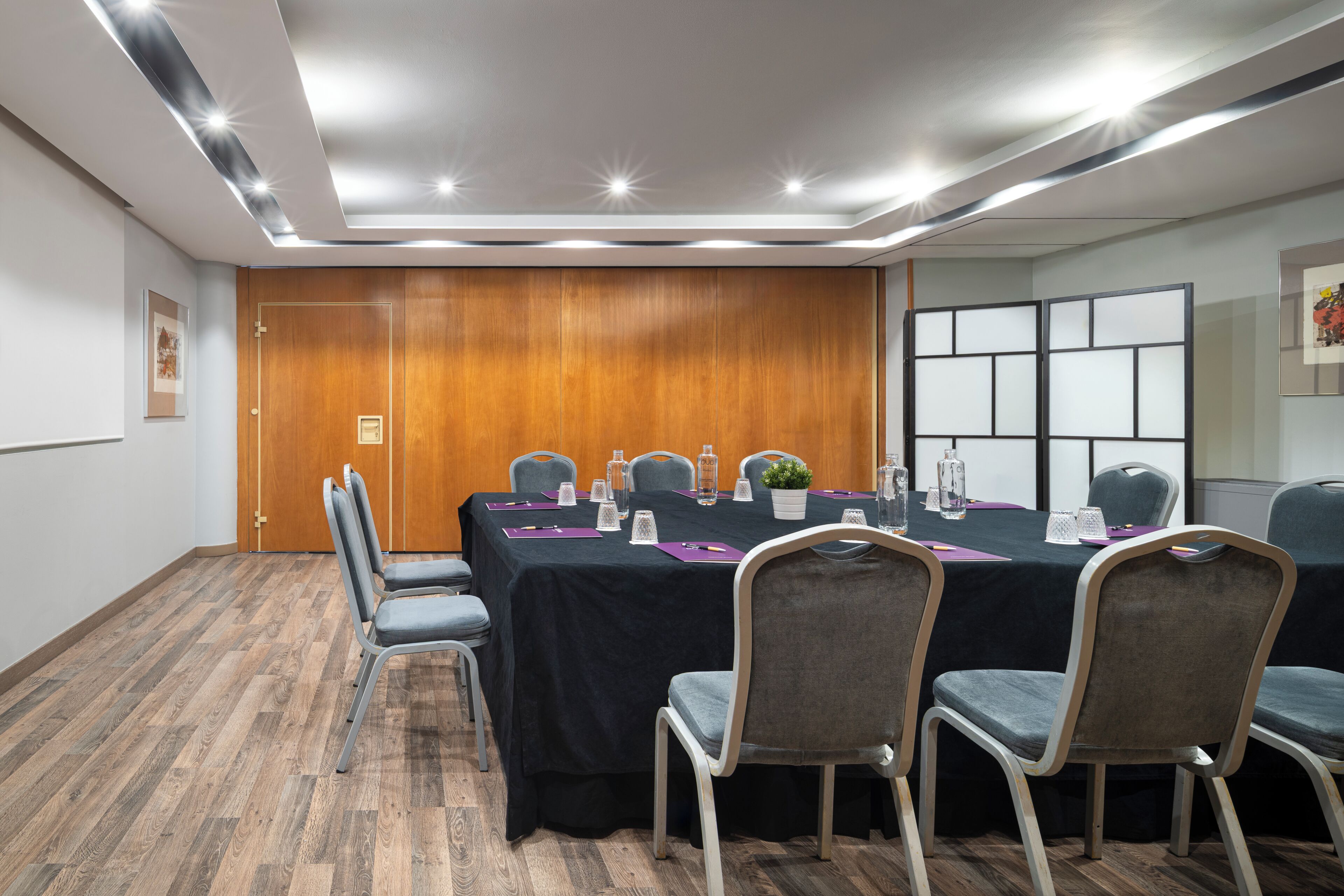 Un salón de conferencias con una mesa larga, sillas y una puerta de madera.