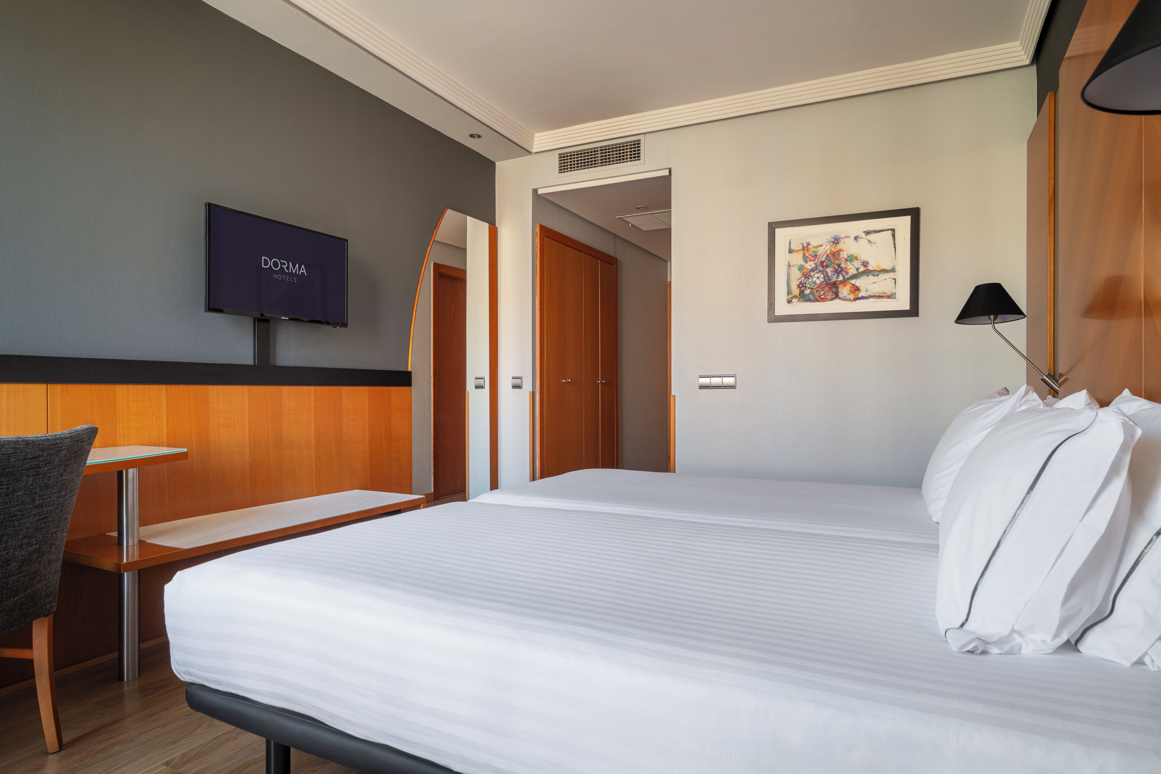 Una habitación de hotel con cama, televisor, escritorio y una silla.