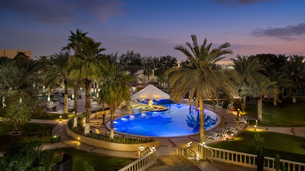A pool area with palm trees, a gazebo, and outdoor seating. - Metropolitan Al Mafraq Hotel (Abu Dhabi)