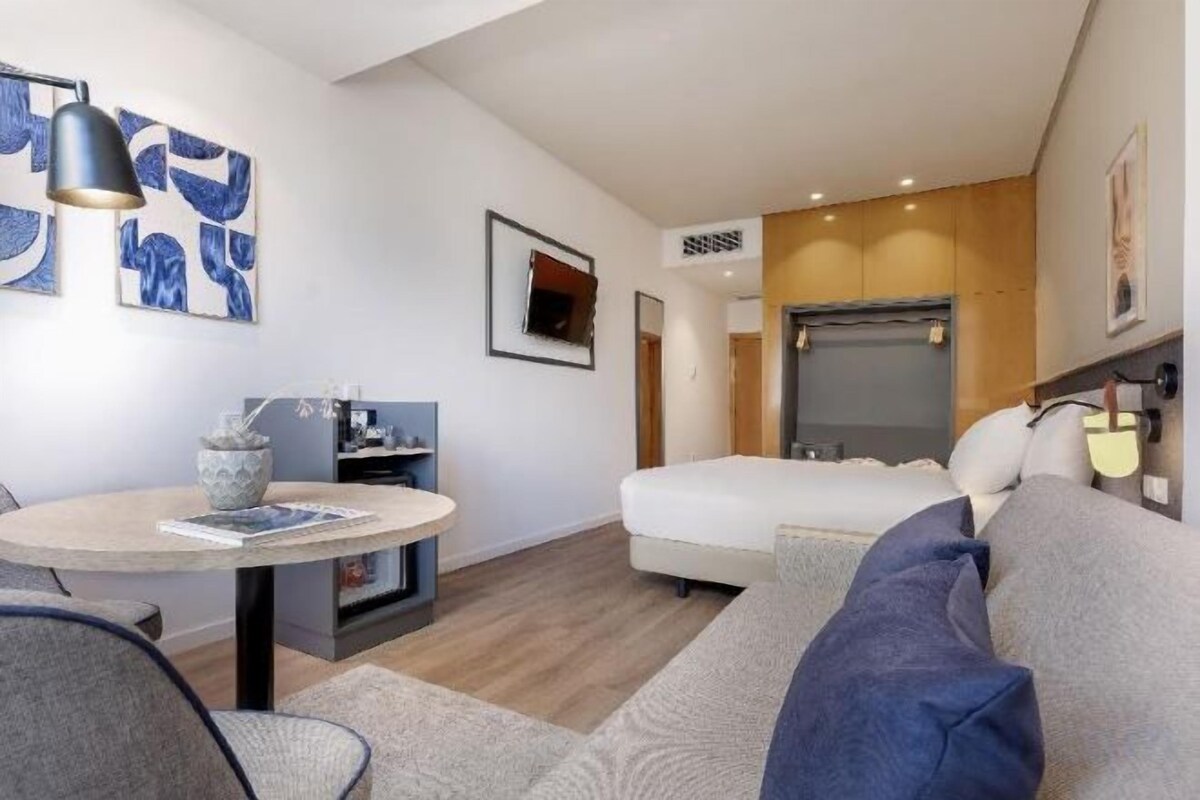 Une chambre d’hôtel moderne équipée d’un lit, d’un canapé, d’une table à manger et d’une petite kitchenette.