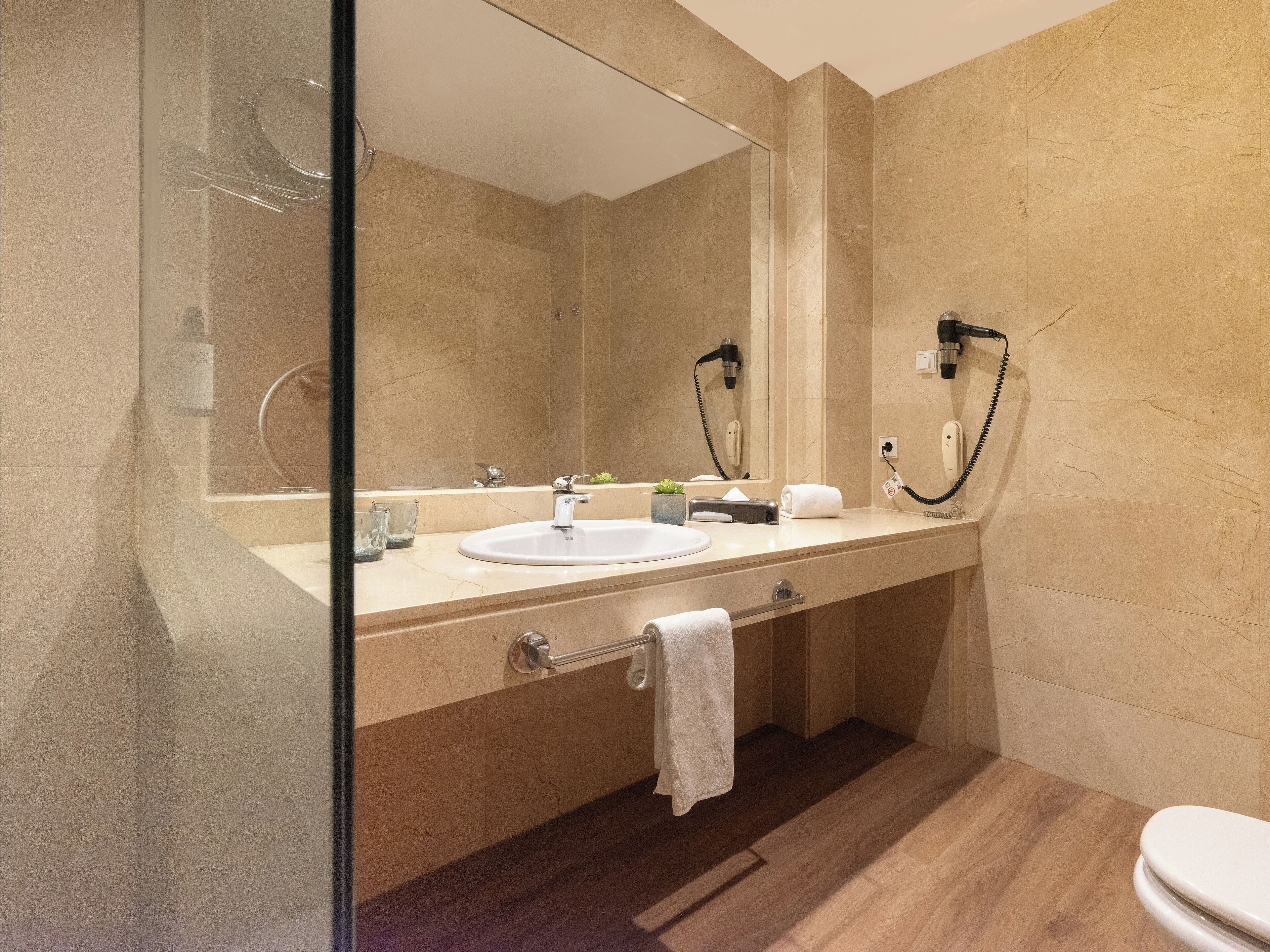 Un baño moderno con un espejo grande, un lavabo, un perchero para toallas y un inodoro.