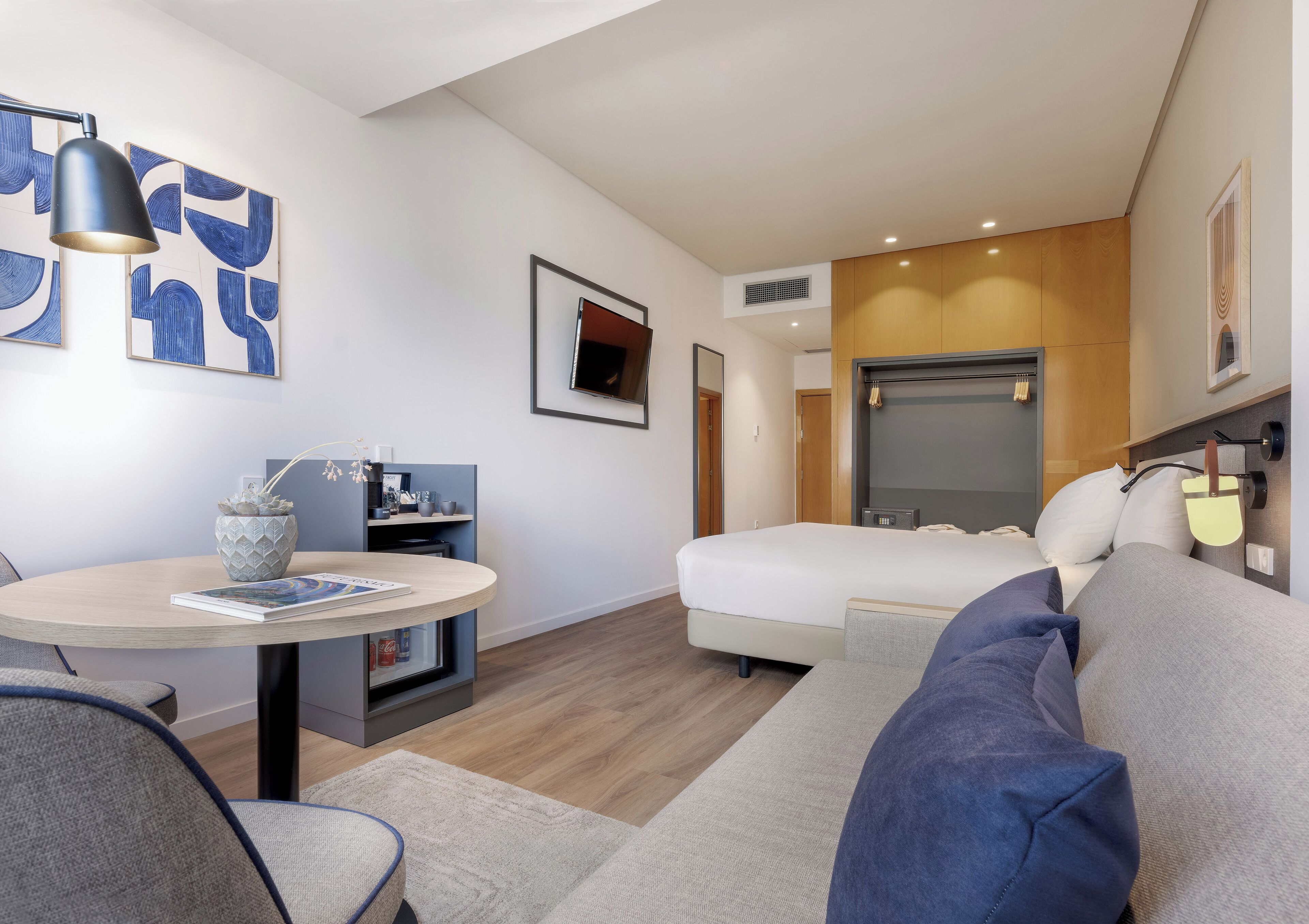 Una habitación de hotel moderna con cama, sofá, escritorio y mesa de comedor.