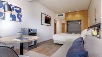 Una habitación de hotel moderna con cama, sofá, escritorio y mesa de comedor.