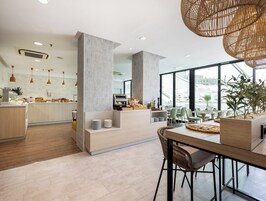 A modern kitchen with a central island, a dining area with a wooden table and chairs, and large windows offering a view of the city.