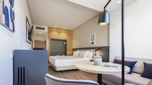 Une chambre d’hôtel moderne équipée d’un lit, d’un bureau, d’une chaise, d’un canapé et d’une lampe.