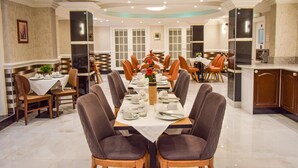 A dining area with a long table set for a meal, surrounded by chairs. - Pembridge Palace Hotel (London)