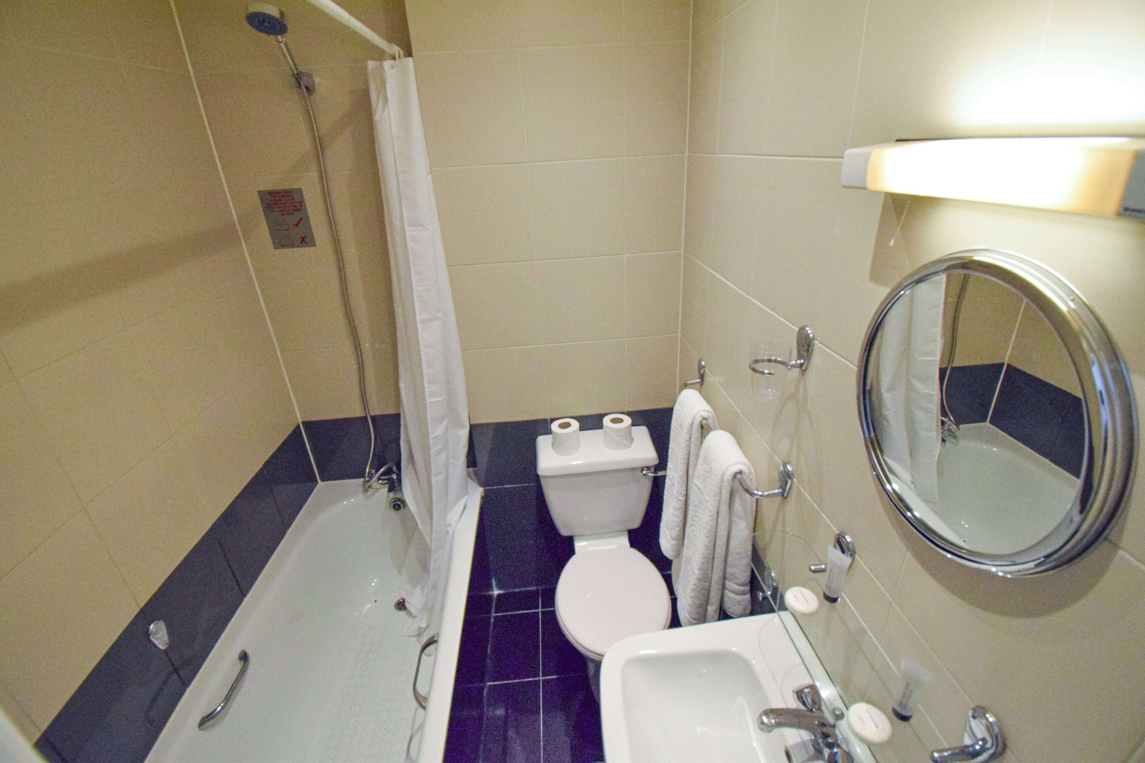 Un baño con bañera, inodoro, lavabo y espejo.