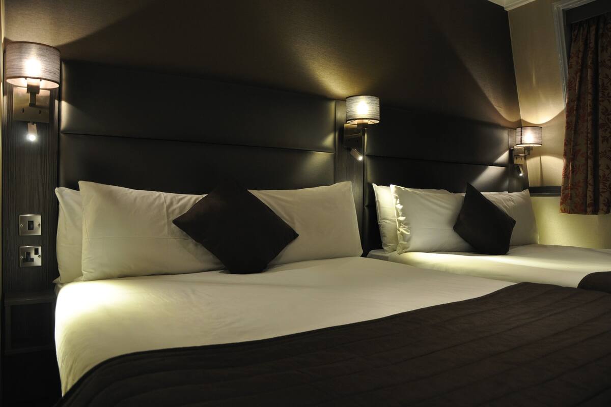 Una camera d'albergo con un letto grande, due comodini e lampade a parete.