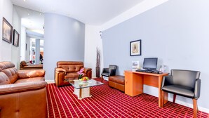 A modern living room with leather sofas, a glass coffee table, and a wooden desk with a laptop. - Brunel Hotel (London)