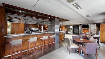 A modern bar area with a counter, stools, and a seating area with tables and chairs.