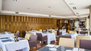 Un restaurante con varias mesas dispuestas para comer, con una decoración moderna que incluye paneles de madera e iluminación empotrada en el techo.