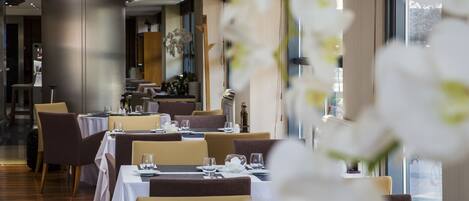 Un restaurante con mesas dispuestas para comer, una zona de bar y vistas al exterior.