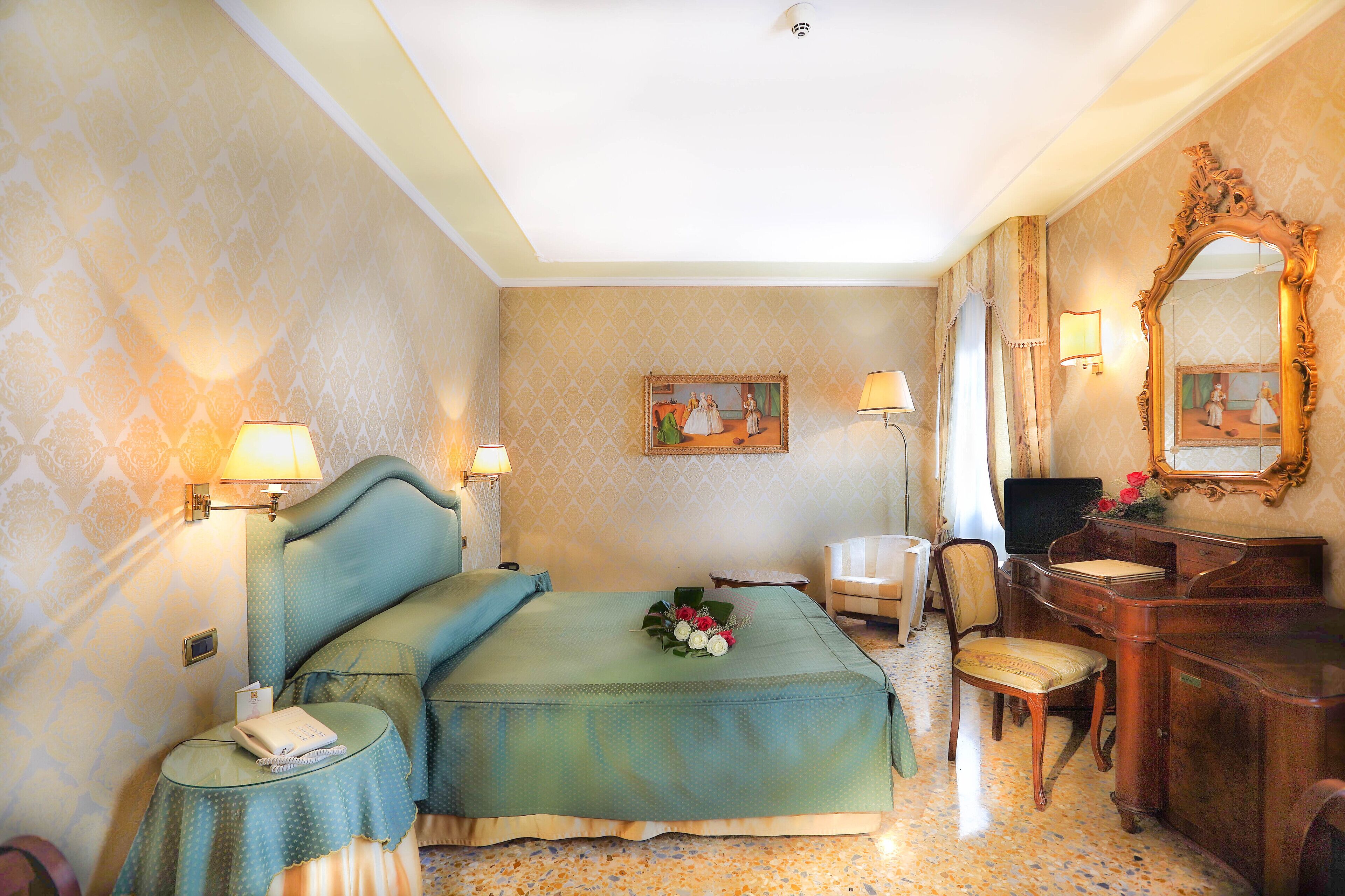 Ein Hotelzimmer mit Bett, Nachttisch, Schreibtisch, Stuhl und Spiegel.