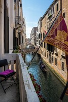 Un canale con una gondola, edifici con balconi e una bandiera.