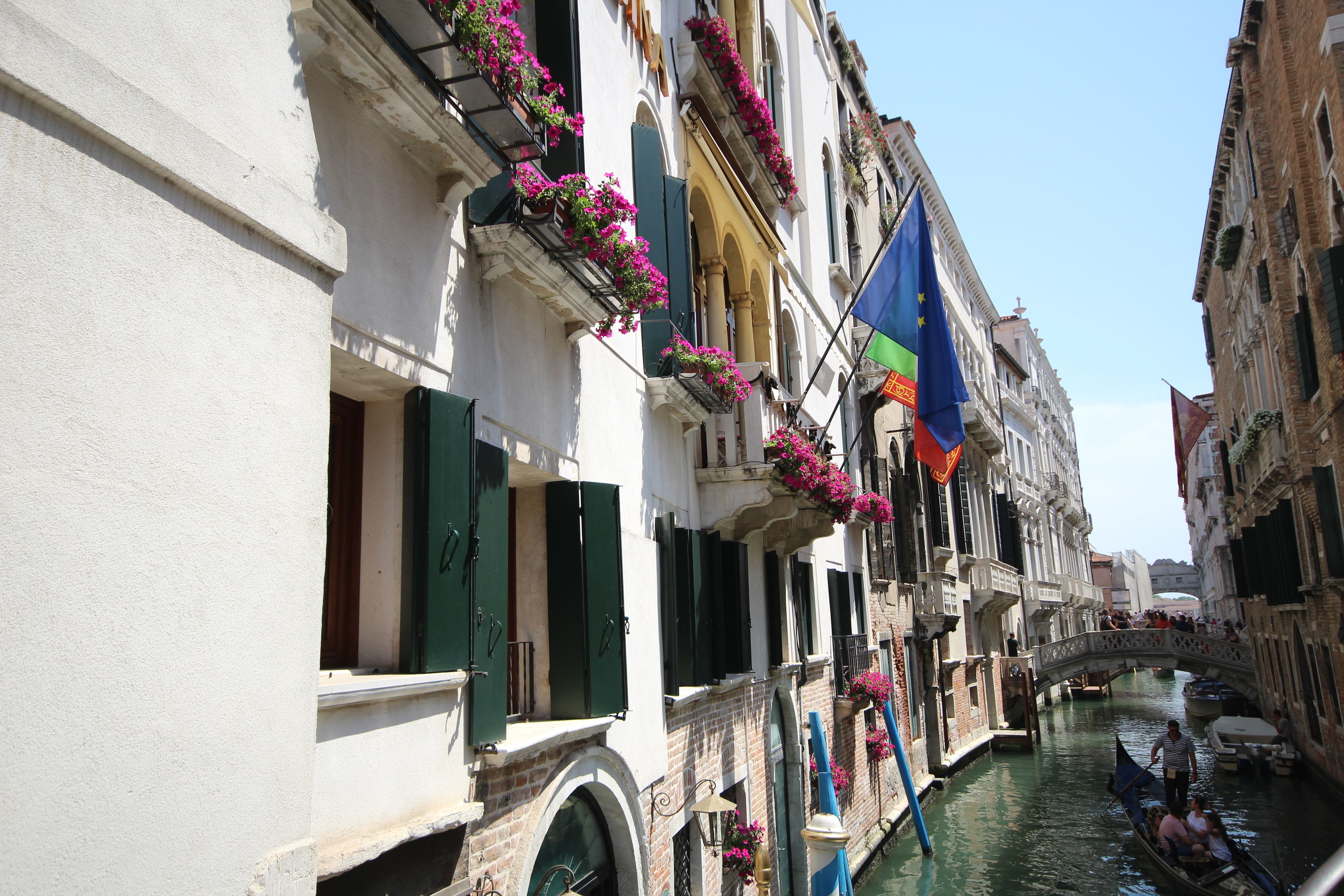 Un canal estrecho flanqueado por edificios, algunos con balcones adornados con flores.