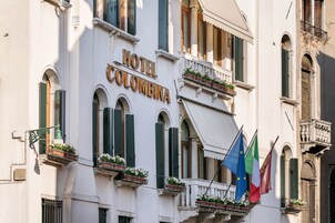 Un edificio con il cartello "HOTEL COLOMBINA" e balconi adornati da fioriere.