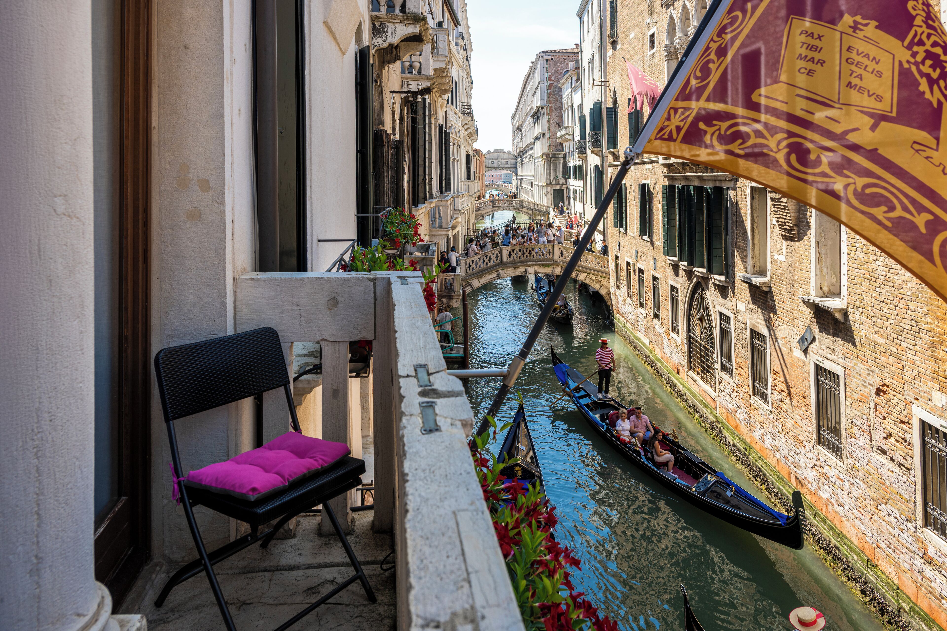 Un canal estrecho con góndolas, un puente y edificios con balcones.