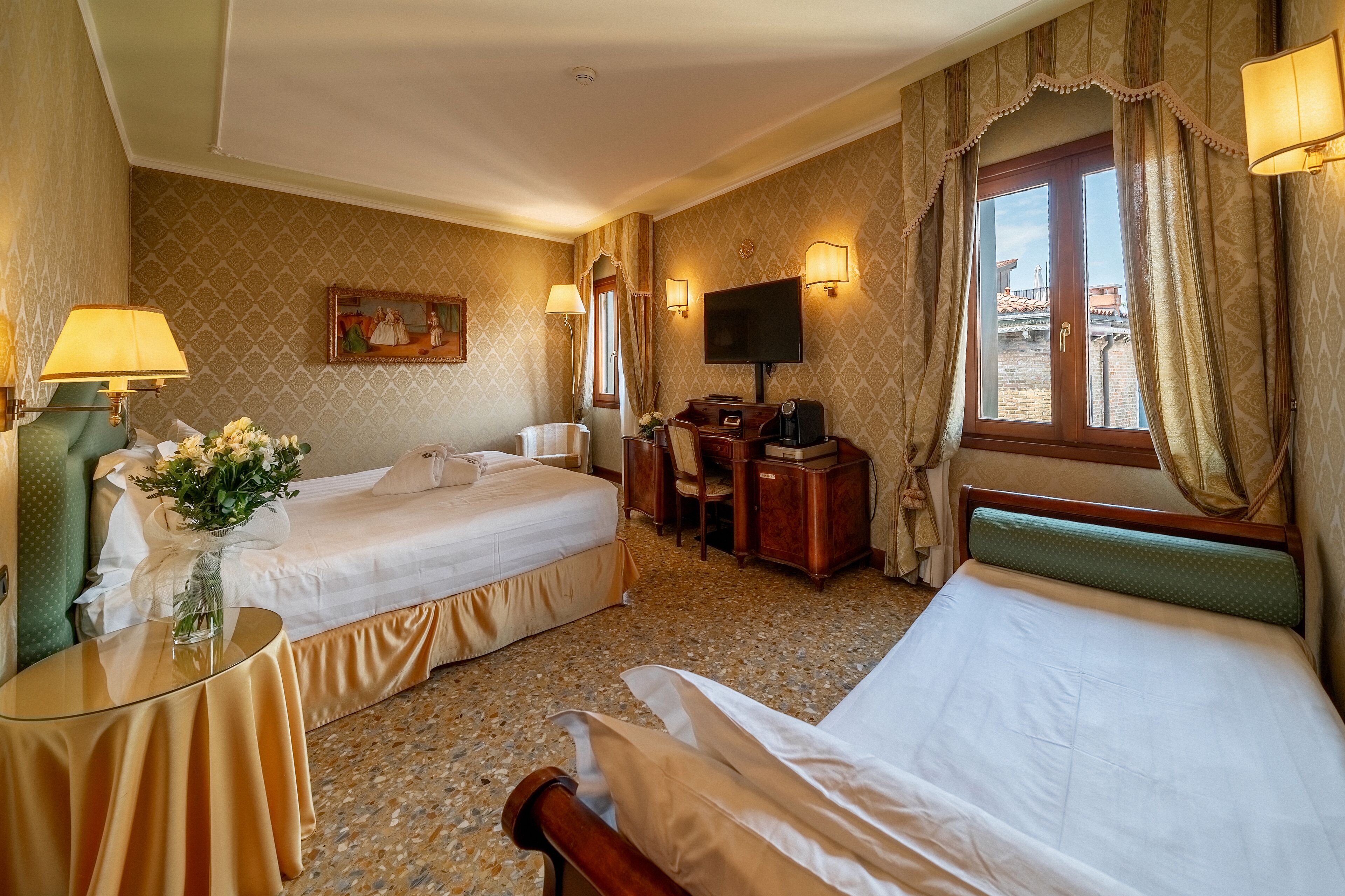 Een hotelkamer met twee bedden, een bureau met stoel, een televisie en een raam met gordijnen.
