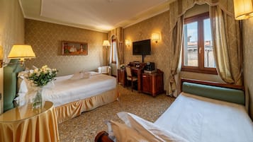 Een hotelkamer met twee bedden, een bureau met stoel, een televisie en een raam met gordijnen.