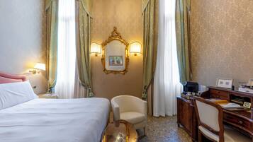 A hotel room with a bed, two chairs, a desk, and a mirror.