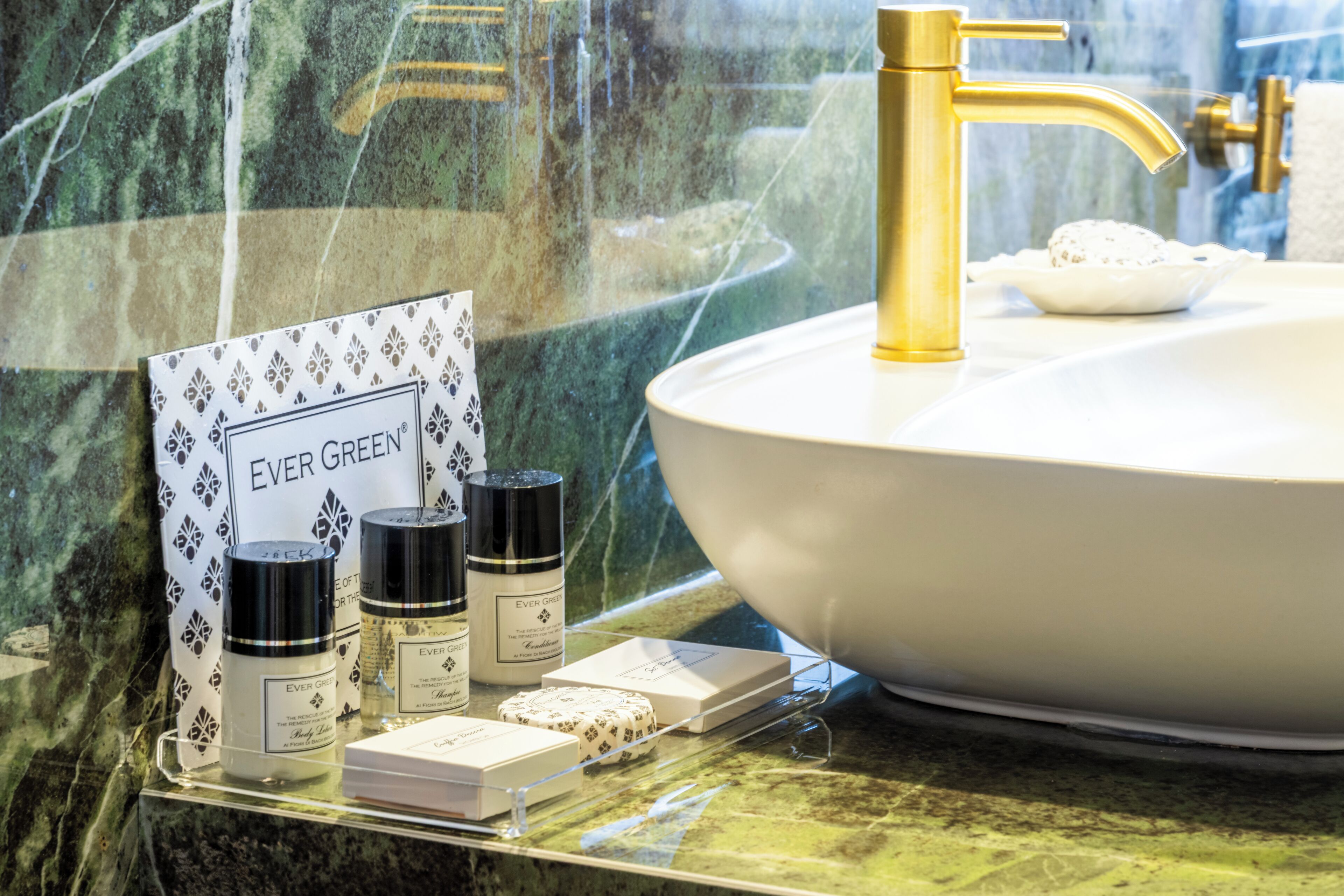 A bathroom with a white sink, gold faucet, and a glass display case containing Ever Green products.