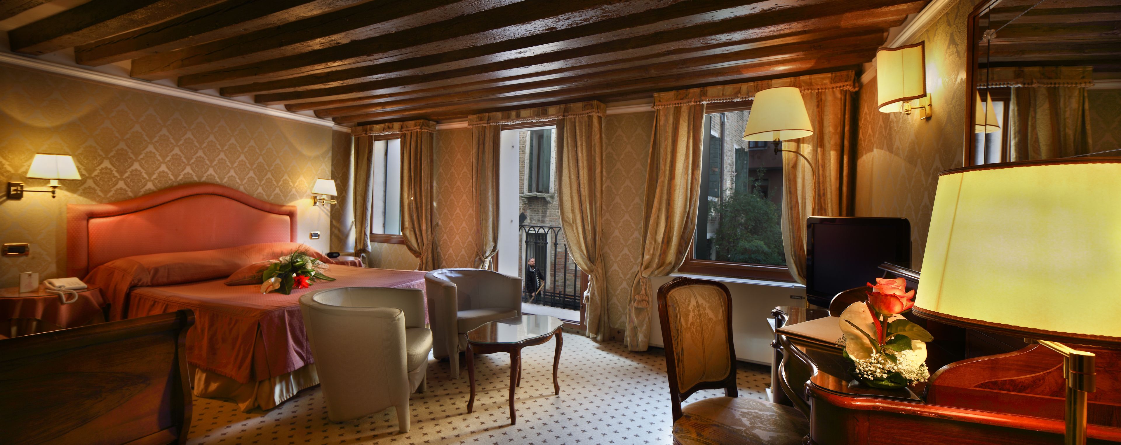 A hotel room with a large bed, a desk, a chair, and a TV.