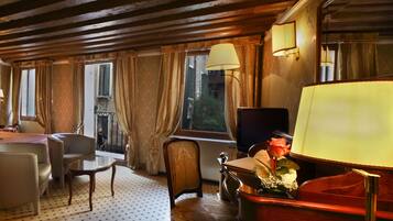 A hotel room with a large bed, a desk, a chair, and a TV.