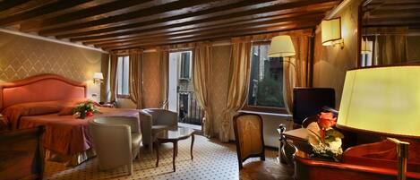 A hotel room with a large bed, a desk, a chair, and a TV.