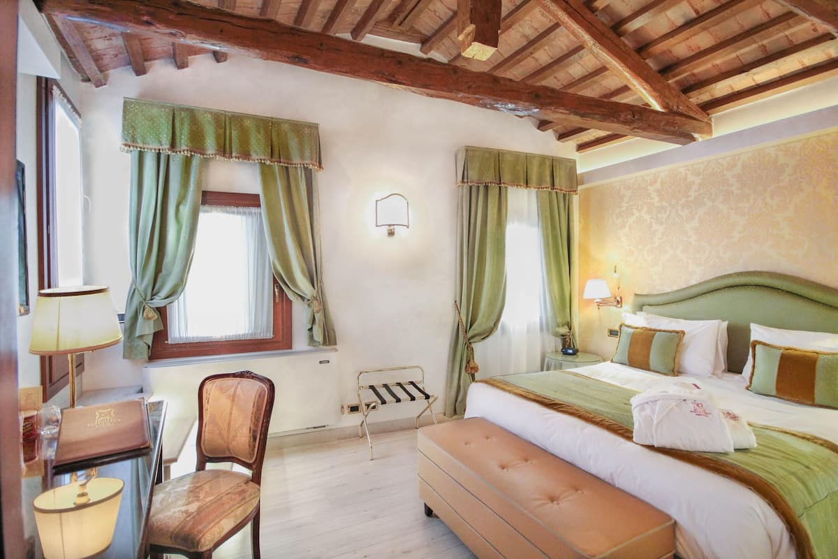 A bedroom with a bed, a chair, a desk, and a window with curtains.