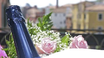 A bottle of champagne with a decorative top, surrounded by pink roses and baby's breath flowers.