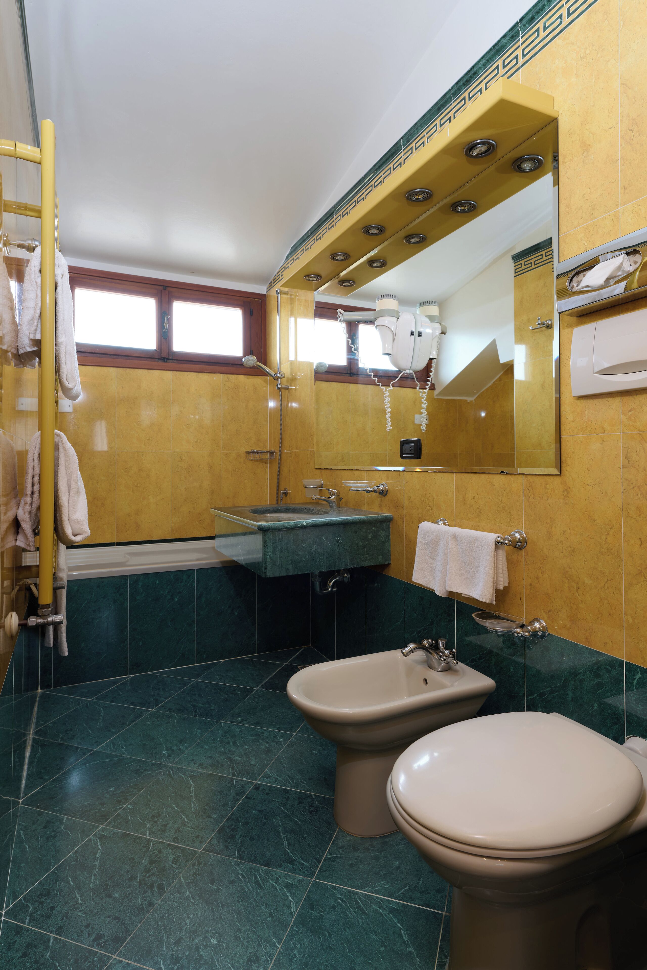 A bathroom with a sink, bidet, and toilet.