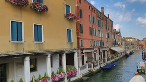 Un canal con barcos, un hotel llamado "Hotel Aricochio" y arquitectura veneciana tradicional.
