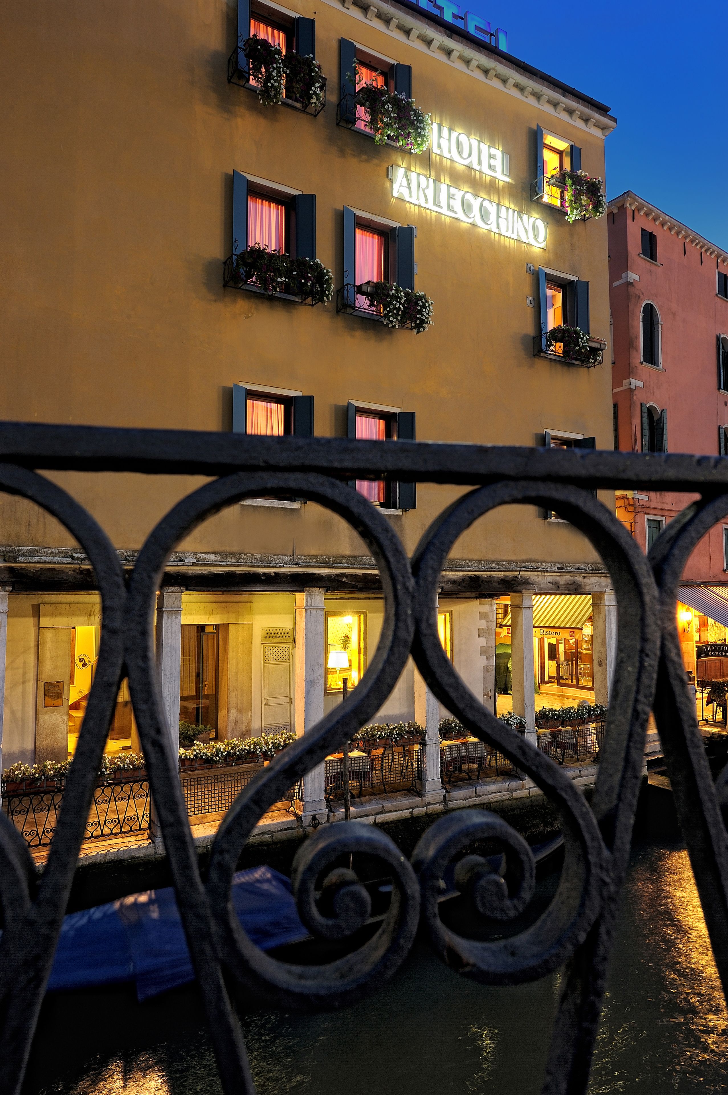 A hotel with a classic facade, multiple windows with shutters, and a sign indicating it is the Hotel Arlecchino.