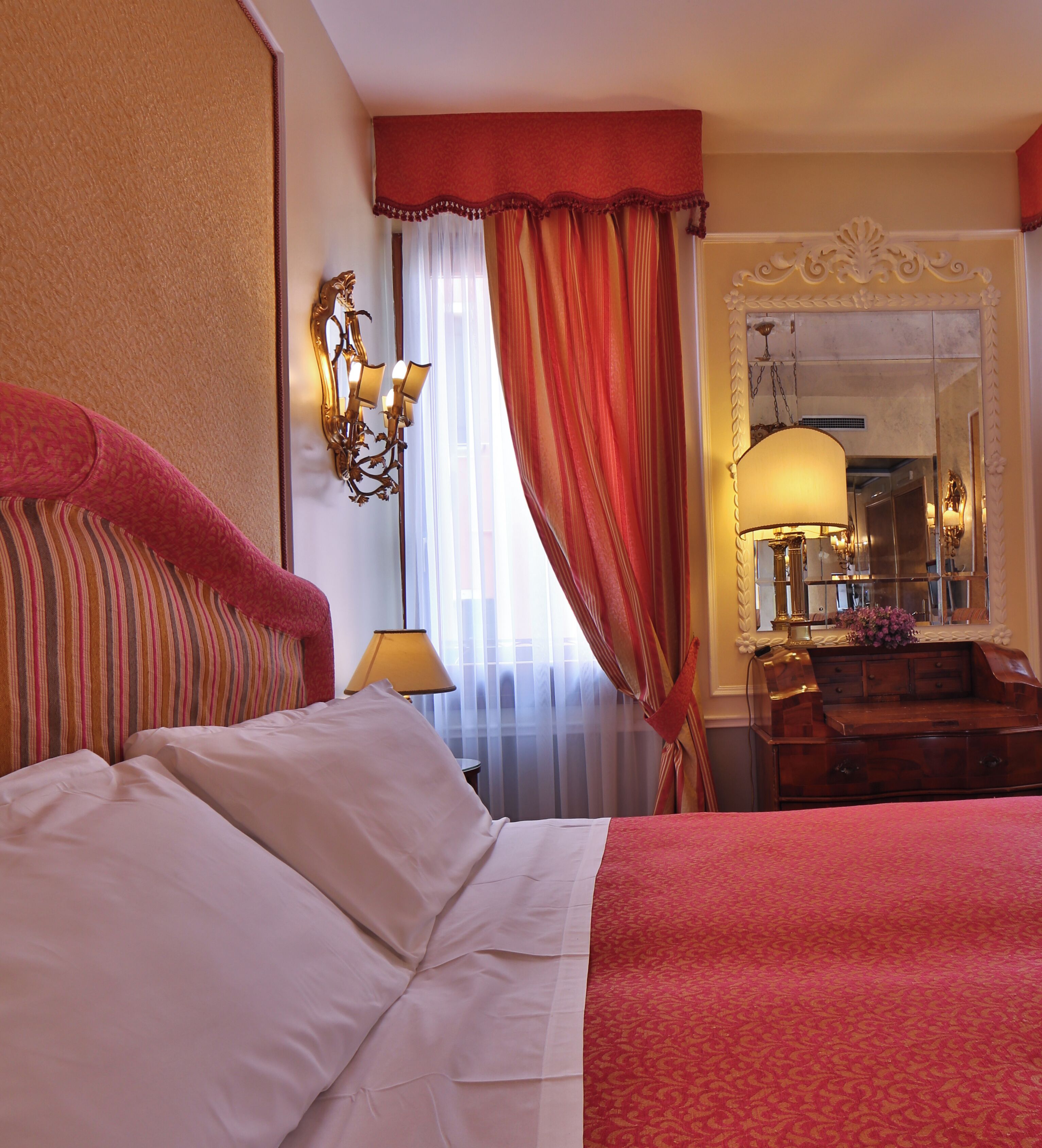 A hotel room with a large bed, a dresser, a mirror, and a window with curtains.