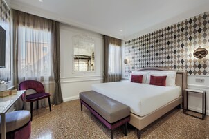 Una habitación de hotel con una cama grande, un escritorio, una silla y un banco.