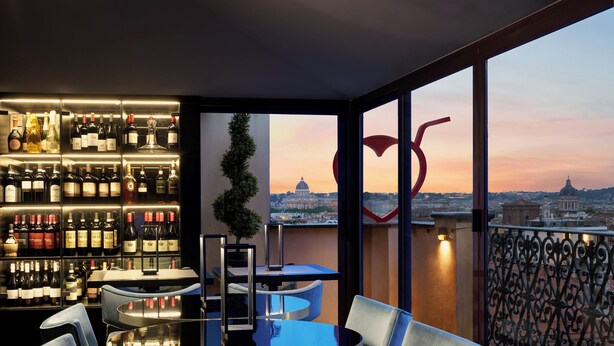 A bar area with a view of a cityscape, including a dome building, and a balcony with a wrought iron railing. - Hotel Barberini (Rome)