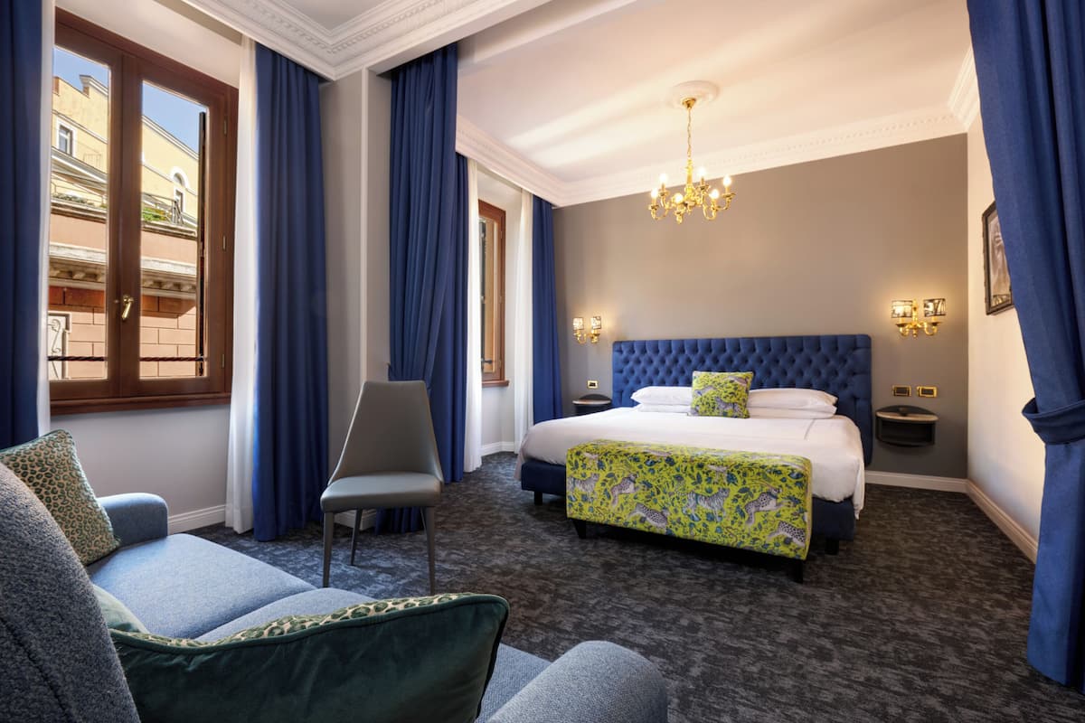 A hotel room with a large bed, a chair, a desk, and a view of the outside.