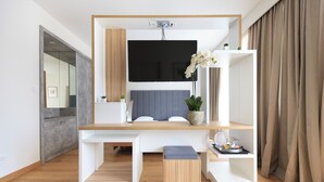 A modern room with a desk, a flat-screen TV, a potted plant, and a bench. - Hotel Suisse (Geneva)
