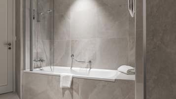 A modern bathroom with a glass-enclosed shower, a white bathtub, and a towel rack.