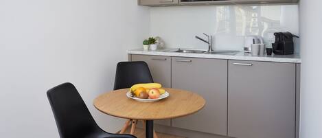 A modern kitchen with a microwave, sink, and a small dining table with chairs.