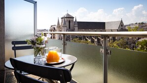 A balcony with a table, a vase with flowers, and a glass of orange juice. - Hotel Suisse (Geneva)