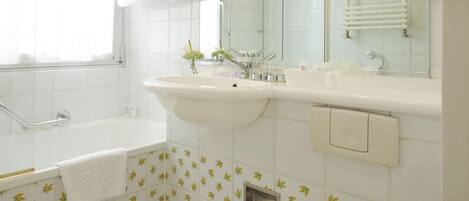 A bathroom with a bathtub, sink, toilet, and a mirror.