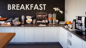 A breakfast buffet with various food items and beverages, a coffee machine, and a sign that reads "BREAKFAST". - Hotel Suisse (Geneva)