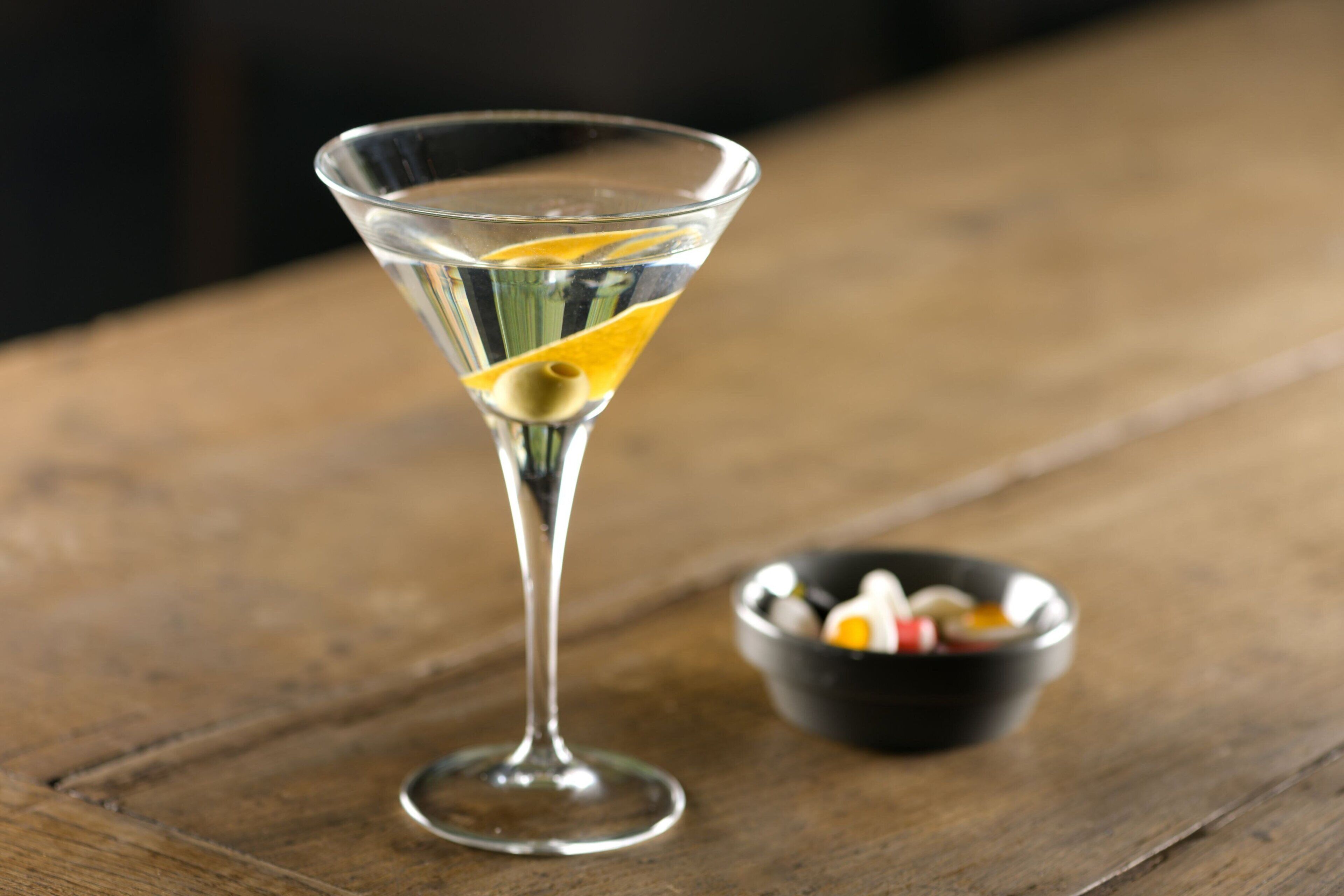 Un verre à martini orné d’une tranche de citron, posé sur une table en bois.