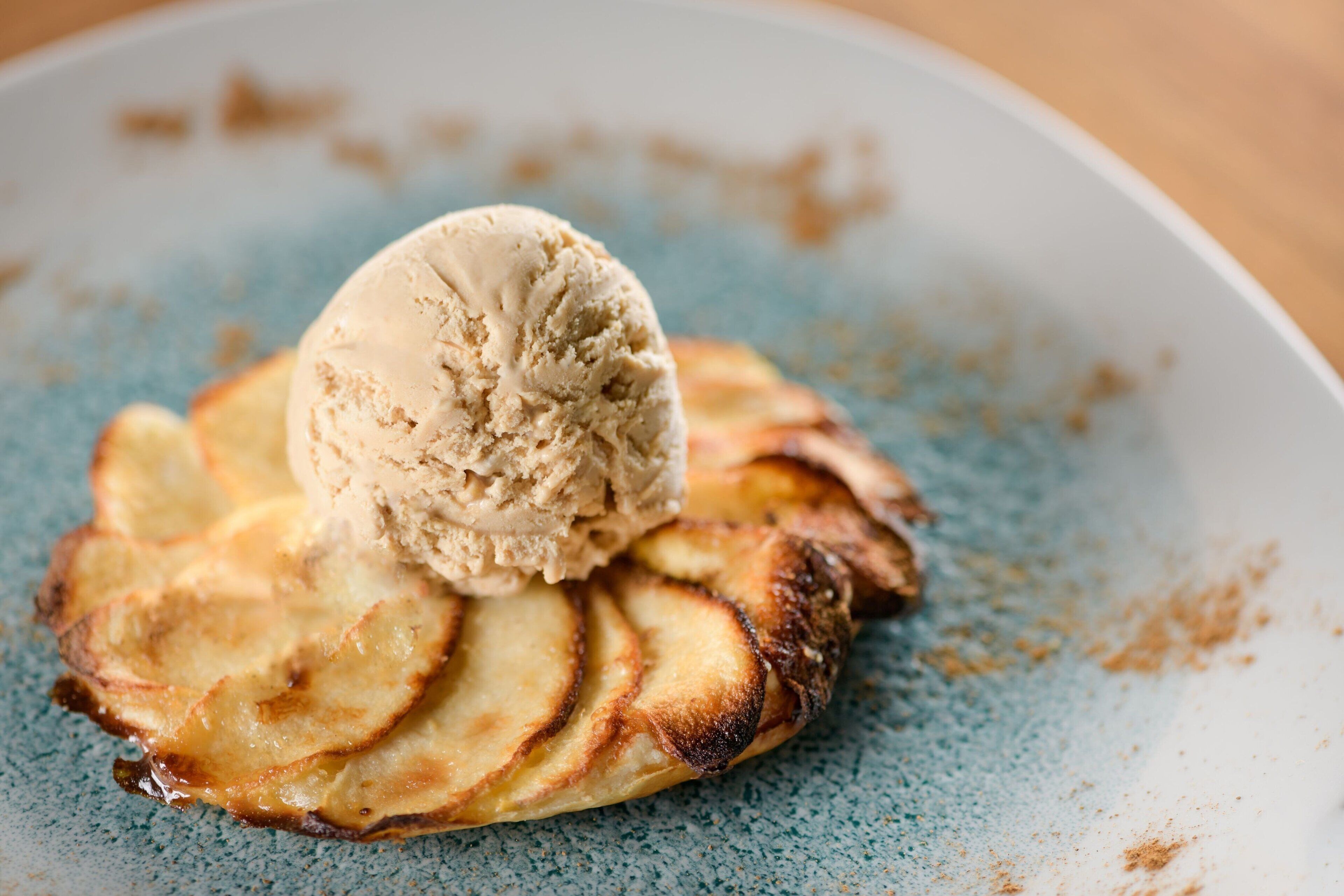 Une assiette de dessert avec des tranches de pommes et une boule de glace.