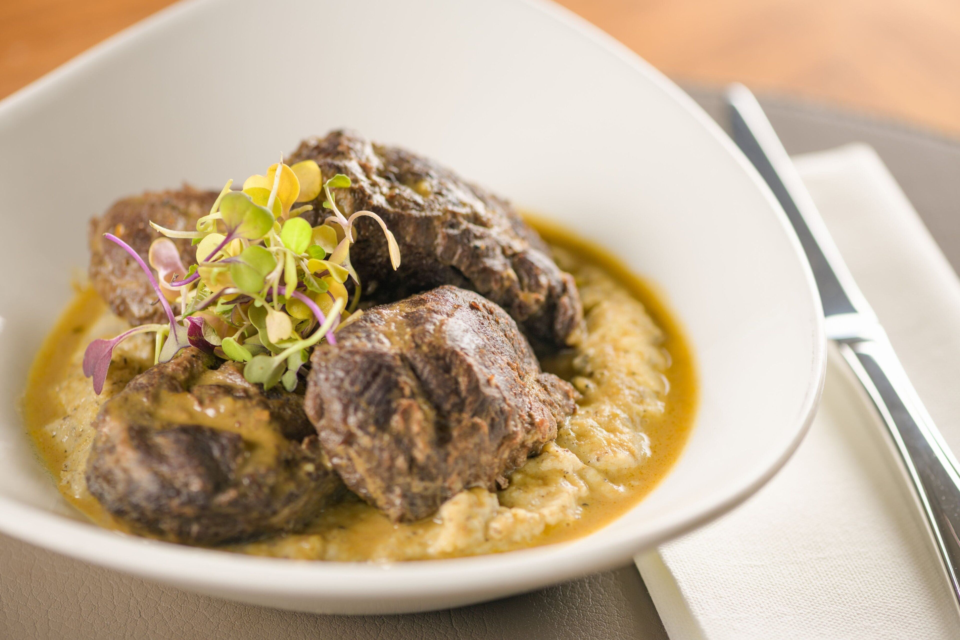 A bowl of food with meatballs and a creamy sauce, garnished with greens.
