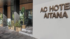 Una entrada de hotel moderna con un gran letrero que dice "AC HOTEL AITANA".