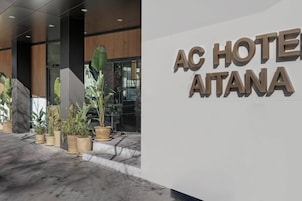 Ein moderner Hotelzugang mit einem großen Schild, auf dem "AC HOTEL AITANA" steht.