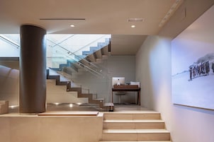 A modern interior with a staircase leading to an upper level, a desk with a computer, and a wall-mounted projection.