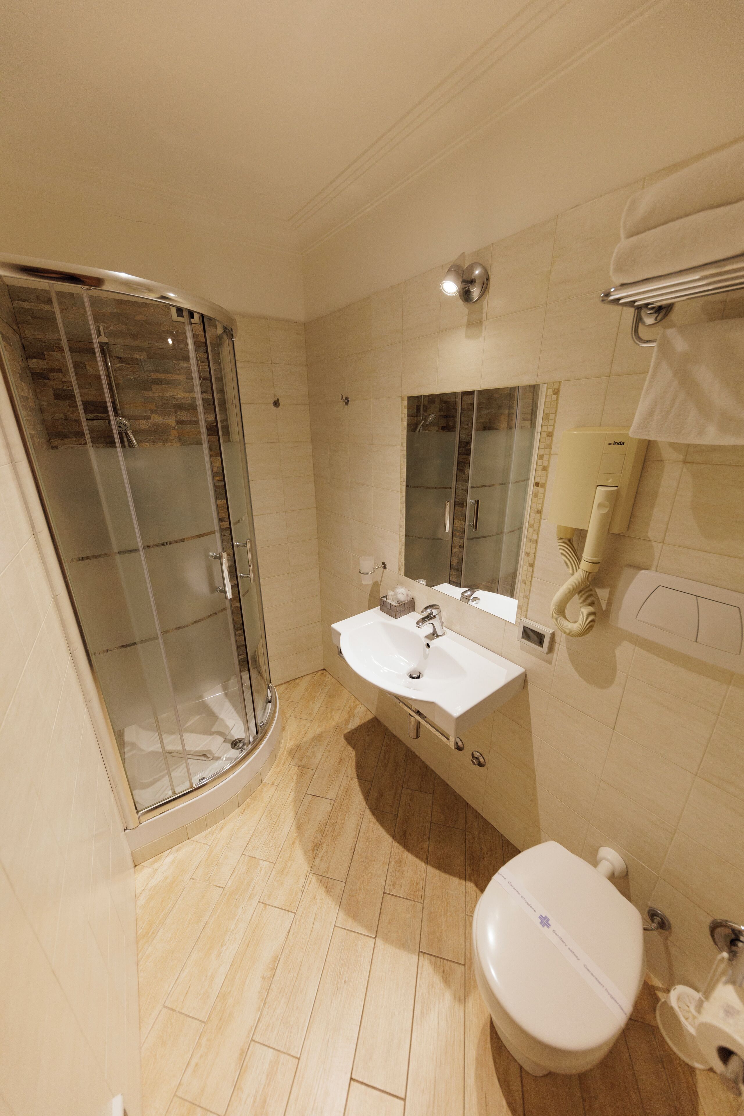 A bathroom with a glass-enclosed shower, a sink with a mirror, and a toilet.